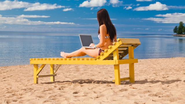 Ragazza in spiaggia su lettino con laptop