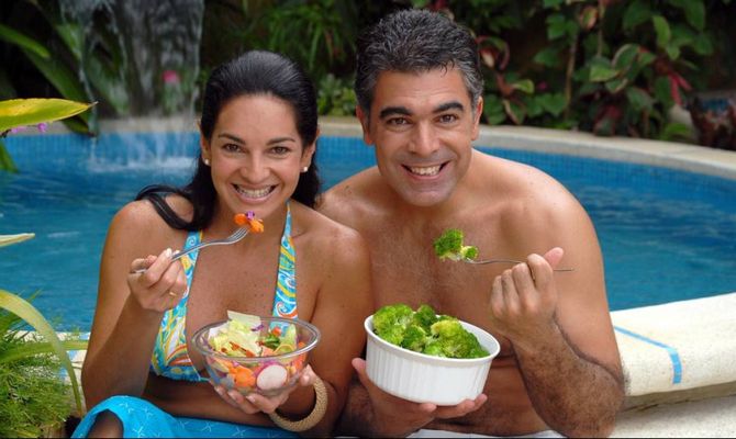 Coppia che mangia insalata davanti a piscina