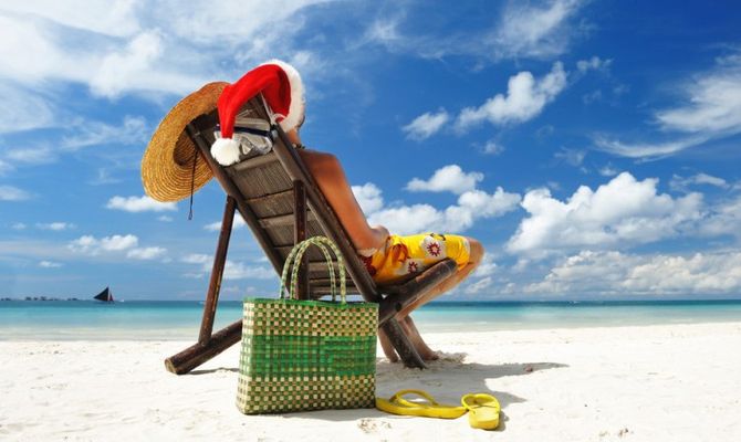 Uomo sulla spiaggia con cappello natalizio